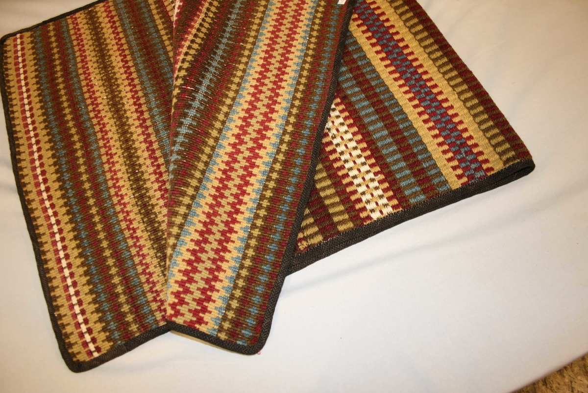 Rektangulært, vove teppe med stripemønster og påsydd kanting.