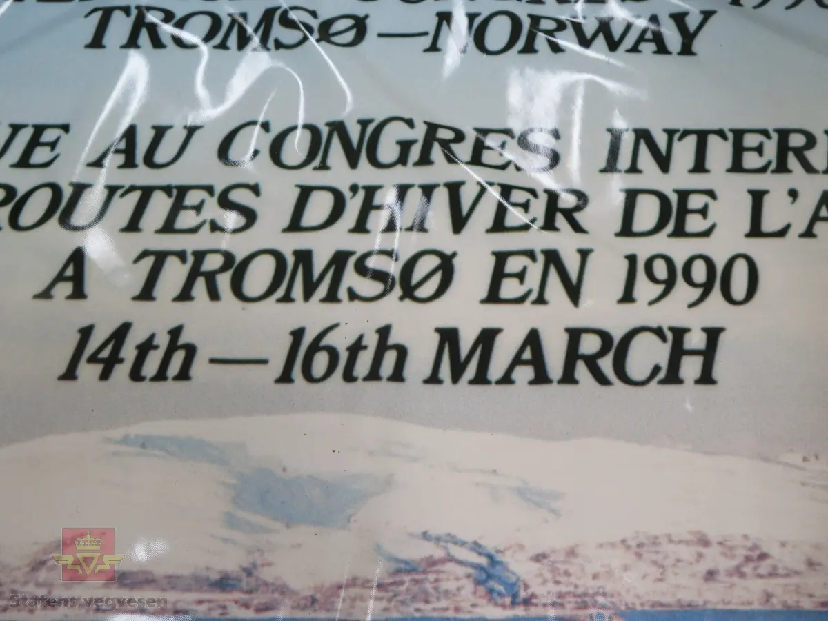 Plakat av plastlignende materiale. Flerfarget. Motivet viser Tromsø by. Plakaten har tekst som informerer om PIARC konferansen i 1990.