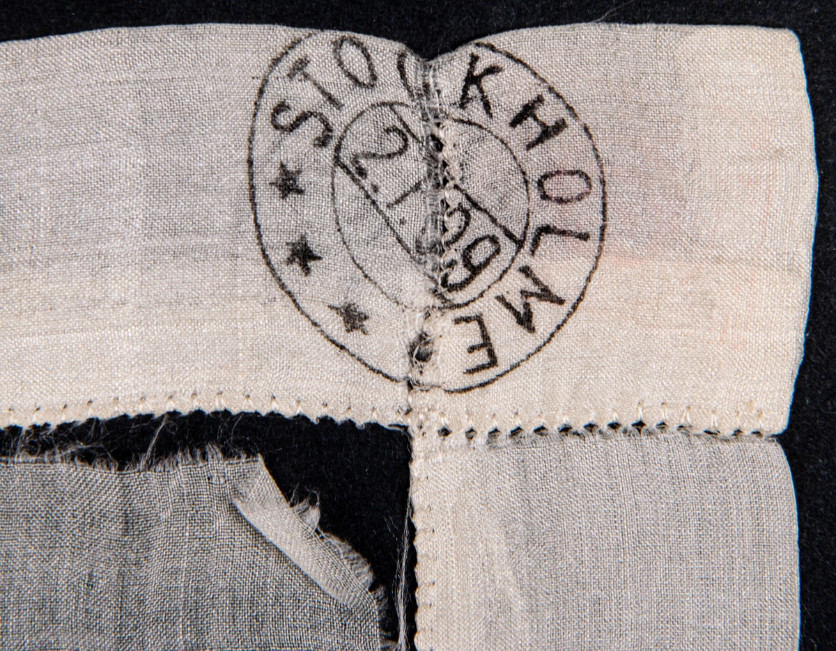 Näsduk av vitt sidentyg med handsydd fåll. Fållen försedd med avbildningar av frimärken samt poststämplar.
