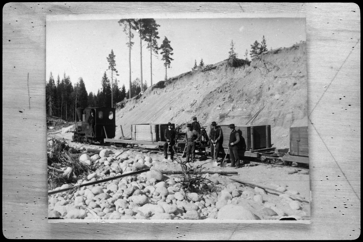 Ångtåg med lok 1 i Västeruds grusgrop. Fjädervagn lastad med grusskymme närmast loket och därefter provisoriska grusvagnar.