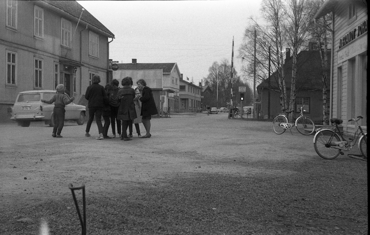 Gatebilde fra Lena, trolig 1962. Bildet er tatt inne fra Lena Foto & Radio i "Raubua", i retning mot jernbaneovergangen. En liten flokk uidentifiserte ungjenter i forgrunnen. Bilen helt til venstre i bildet er en Skoda Octavia varebil/stasjonsvogn fra tidlig 1960-tall. Legg merke til registreringsnummeret. Det er av den såkalte telefonnummer-serien som ble tatt i bruk i Oslo etter at A-serien var oppbrukt.