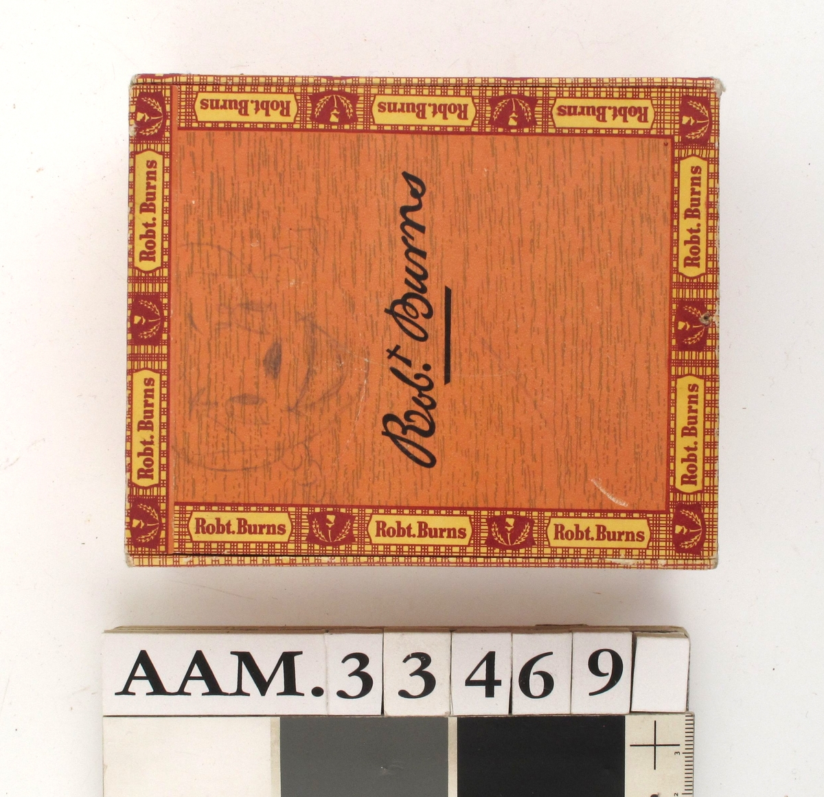 Eske av tynne treplater, påklebet papir med trykt mønster og tekst på alle flater. Brun trestruktur, ellers rød, gul og sort farge. Inneholder brukte frimerker (norske og amerikanske)  fra ca. 1970.