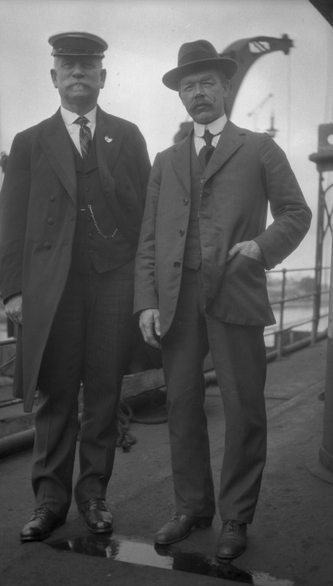 To menn i dress ombord på D/S STORFOND, kaptein Waage til venstre.