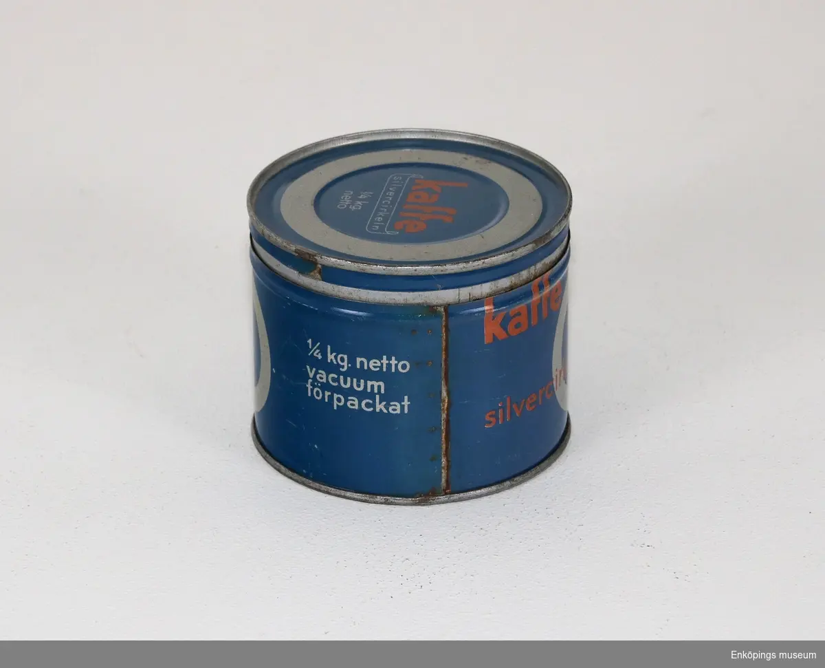 Rund blå kaffeburk med texten: "Kaffe silvercirkeln kopperativa kaffe rosterierna 1/4 kg. netto vacuum förpackat".