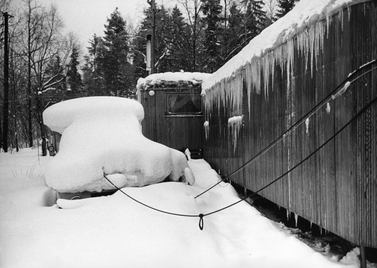 Romskt läger i Ekstubben 1963. Bostadsvagnarna är täckta i snö och istappar hänger från taken.
