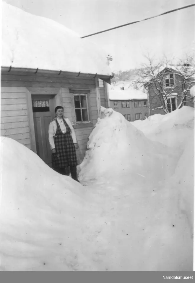 En kvinne foran et hus, (vinter).