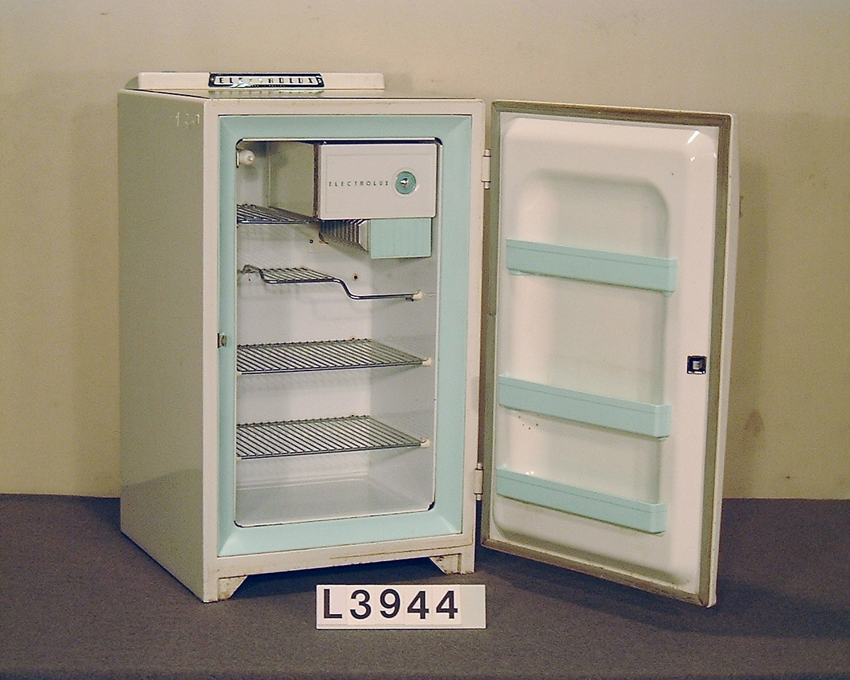 Table Top kylskåp värmedrivet. Handtaget är kromtat. Ovan på skåpet finns en linoleum skiva i gråspräckligt mönster. Kylregulatorn sitter också ovanpå kylskåpet. Kylskåpet har en volym på 85 liter. Bitar