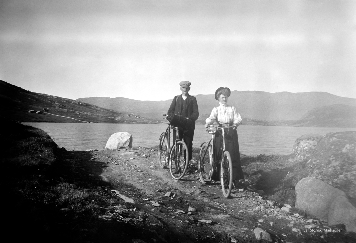 Mann og kvinne med sykkel ved fjellvann. Antatt Sjodalen