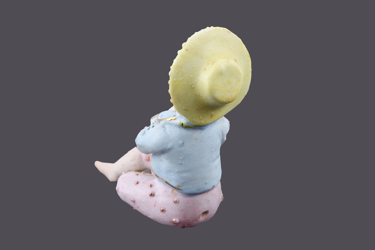 Porselensfigur som forestiller et sittende barn.