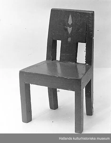 Dockskåpsmöblemang, bestående av :a) soffa i trä, rödmålad, längd: 19 cm, bredd: 5 cm, höjd: 6,7 cm. b) stol i trä, rödmålad med målad utsmyckning i grönt och gult på ryggstödet. Längd: 5,2 cm, bredd: 3,5 cm, höjd: 8,2 cm. c) Bord i trä, rödmålat, runt. Höjd: 6 cm, diameter: 10,5 cm.