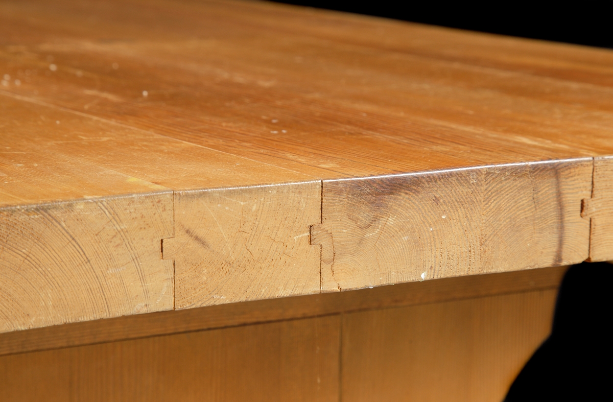 Ett större bord av furu i s.k. allmogestil. Profilerade ben med mittslå. Bordet har använts som skrivbord.