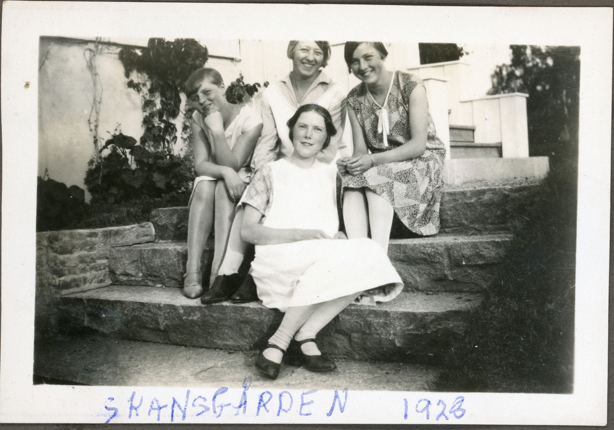 Elever fra husmorskolen på Skansgården, Kongsvinger, 1928. Fire unge kvinner sittende i steintrapp utenfor huset. Piken i midten bak er Sylvia Larsen (f. Digerud) fra Vinger. 
