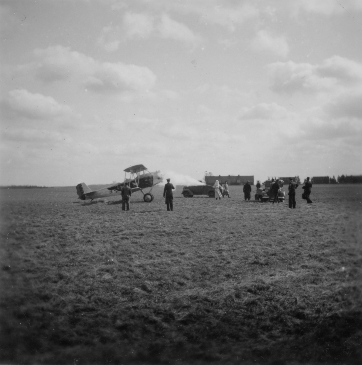 Brand i flygplan SK 8 på flygfältet på F 3 Malmen. Vid avsiktlig eldning av det enda exemplaret av SA-12, mars 1939. En person i arbete. Militärer i rörelse kring planet.
