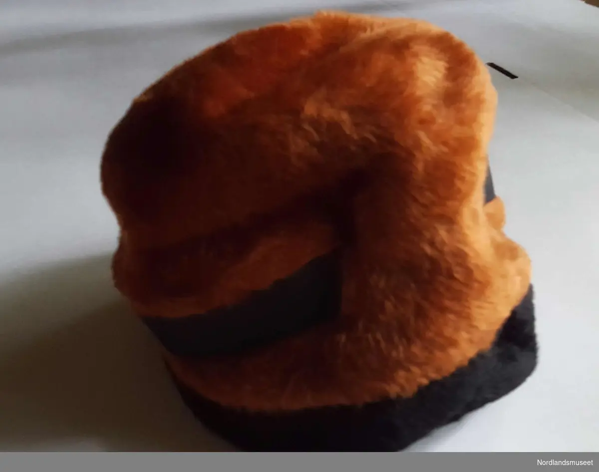 Hatten er brun med sort kant og sort linning i type juksepels