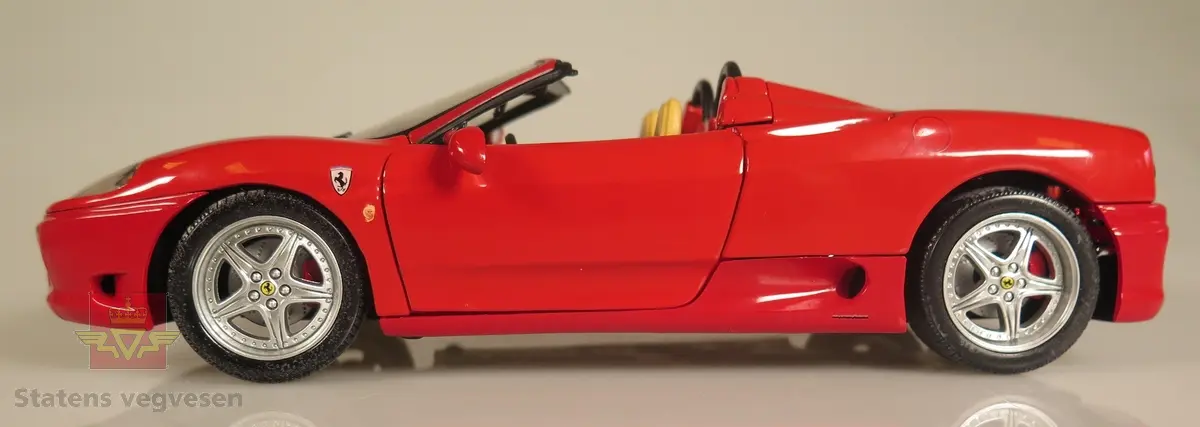 Primært rød modellbil laget av metall og er høyt detaljert. Den er utstyrt med funksjonellt ratt i tillegg til dører, panser og bagasjelokk som kan åpnes og lukkes. Skala: 1:18