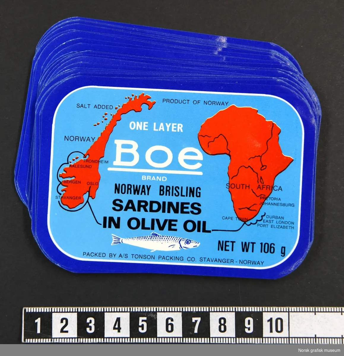 Blå etikett, med mørkere blå bord. Norge og det afrikanske kontinent i rødt. 

"Norway brisling sardines in olive oil"