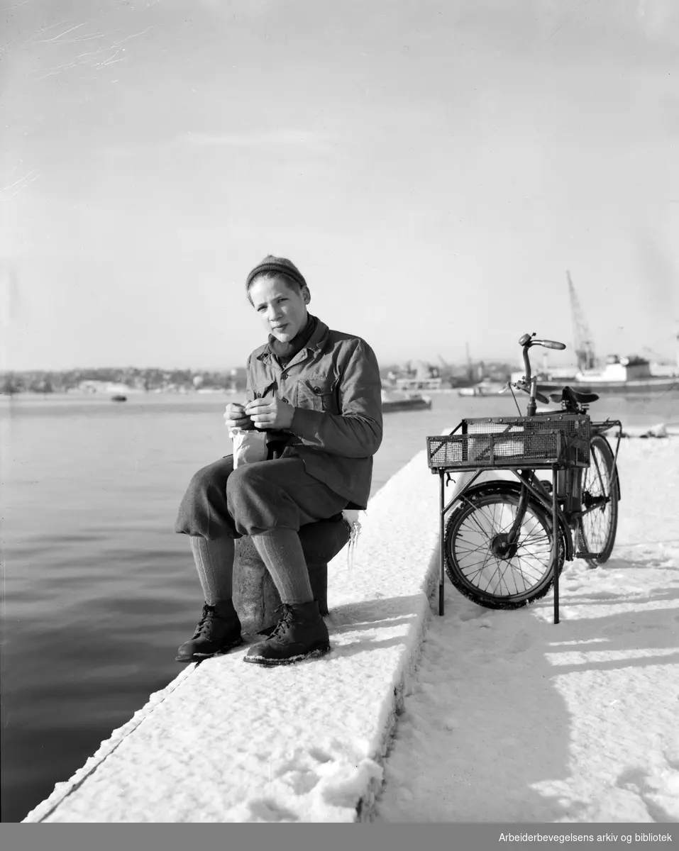 Visergutt Leif Hedemann tar en pause på bryggekanten. Spiser reker. Februar 1949.