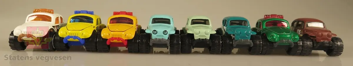 Samling av flere modellbiler. 2 biler er gule, 3 biler er blå, 1 bil er hvit, 1 bil er grønn og 1 bil er brun. Alle er laget av metall og har en skala på 1:57