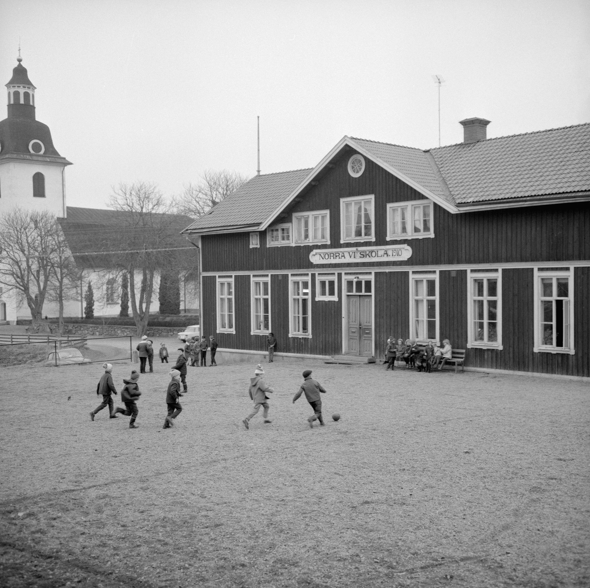 Året är 1964 och i sinom tid kommer det att vara slutlekt på skolgården till Norra Vi kyrkskola. Efter skolans nedläggning 1967 fick byggnaden ny funktion som församlingshem.