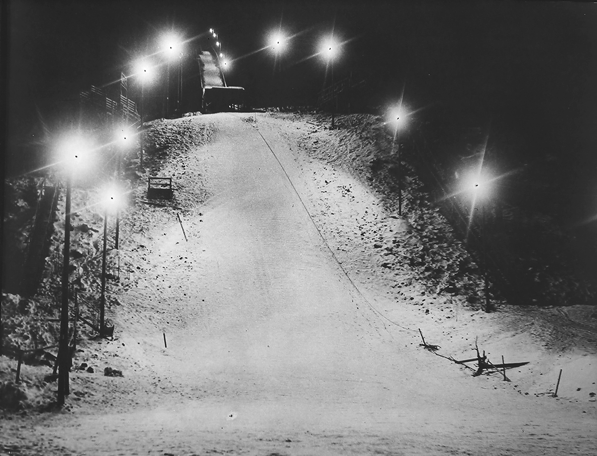 Hoppbakke med lys om kvelden. Philips Norsk A/S. Fotografert 1939.