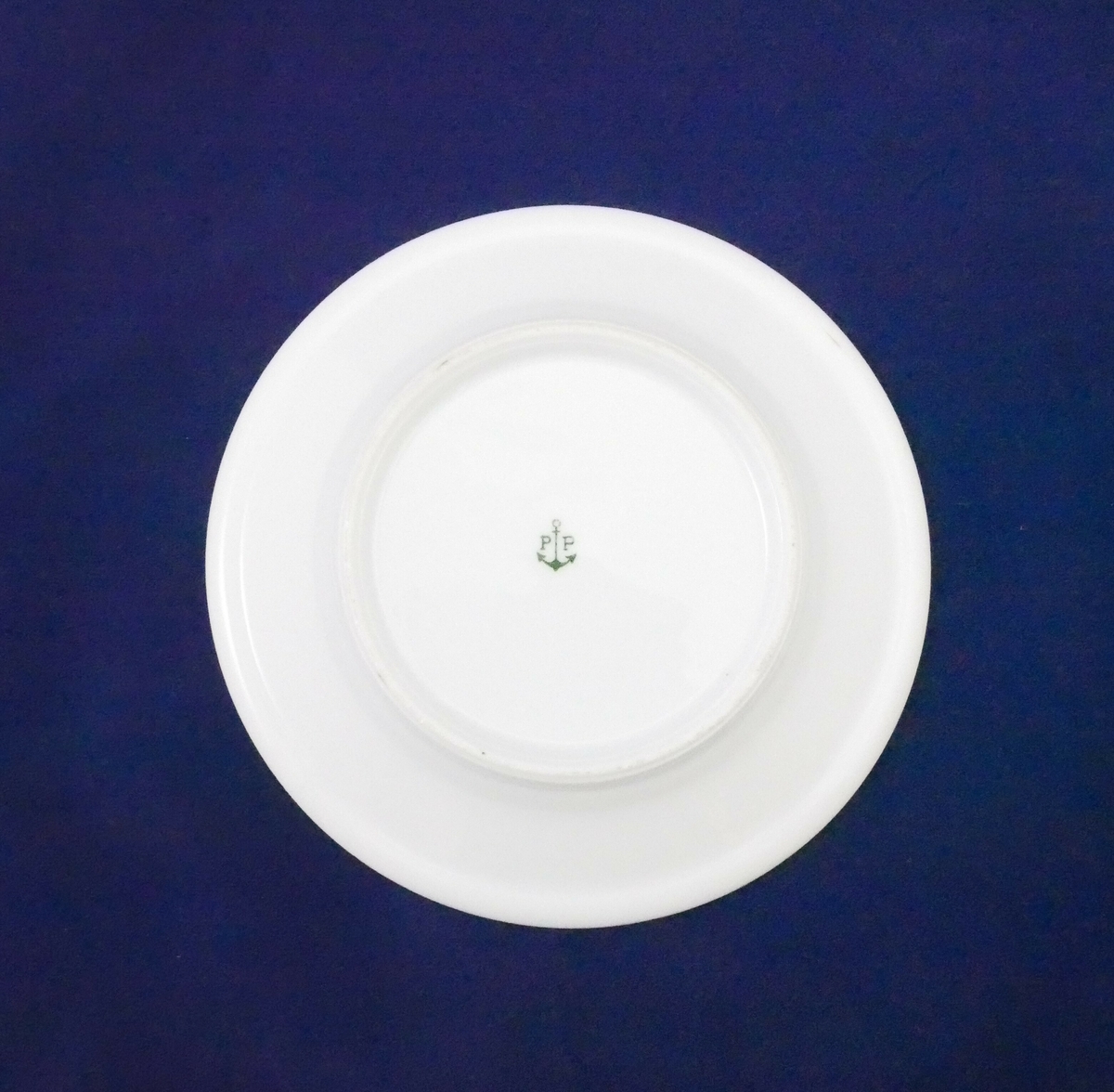 Hvit tallerken i porselen med påskrift med sorte bokstaver

Påskrift: 
H. HJØRNEVIK // FLORØ