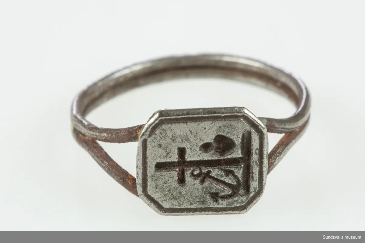 Ring av järn med symbolerna för tro, hopp och kärlek; kors, ankare och ett brinnande hjärta, graverade på klacken.
