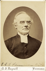 Foto av en äldre man med glasögon, klädd i prästrock med prä