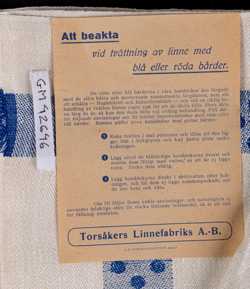 Oklippt, maskinvävd handduksväv av hellinne tillverkad vid Torsåkers linnefabriks aktiebolag. Vävd i tuskaft med naturfärgad botten med blåa effektränder. Försedd med pappersetiketter med tillverkarens emblem.