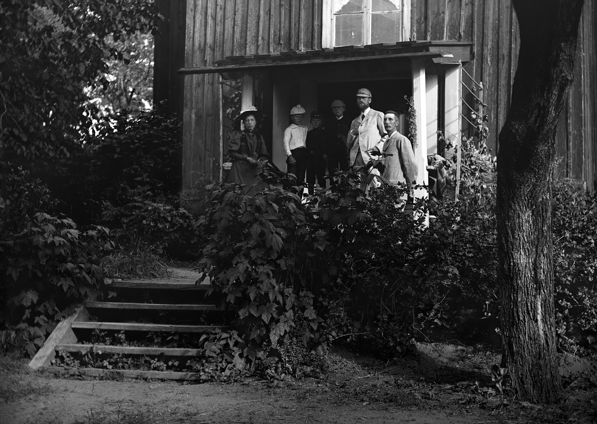 Familjen Hallin bestående av Karl Johan Hallin och hustrun Hedvig Durling med sönerna Uno, Arne och Sigvard emellan sig på verandan till deras hem Ramsdal i Sankt Anna. Längst till höger står morbrodern och fotografen Emil Durling. Året är 1895.