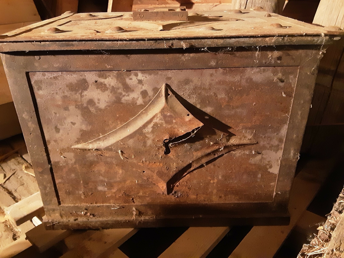 "Bly"-tung kiste. Malt metall. Håndtak av jern på 2 sider. Dekorert med stjerneformet metallpå lokket og på fronten. 
