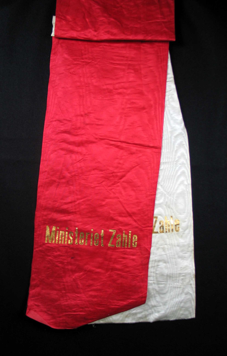 Begravelsessløyfe i hvit og rød silke med tekst i gull.