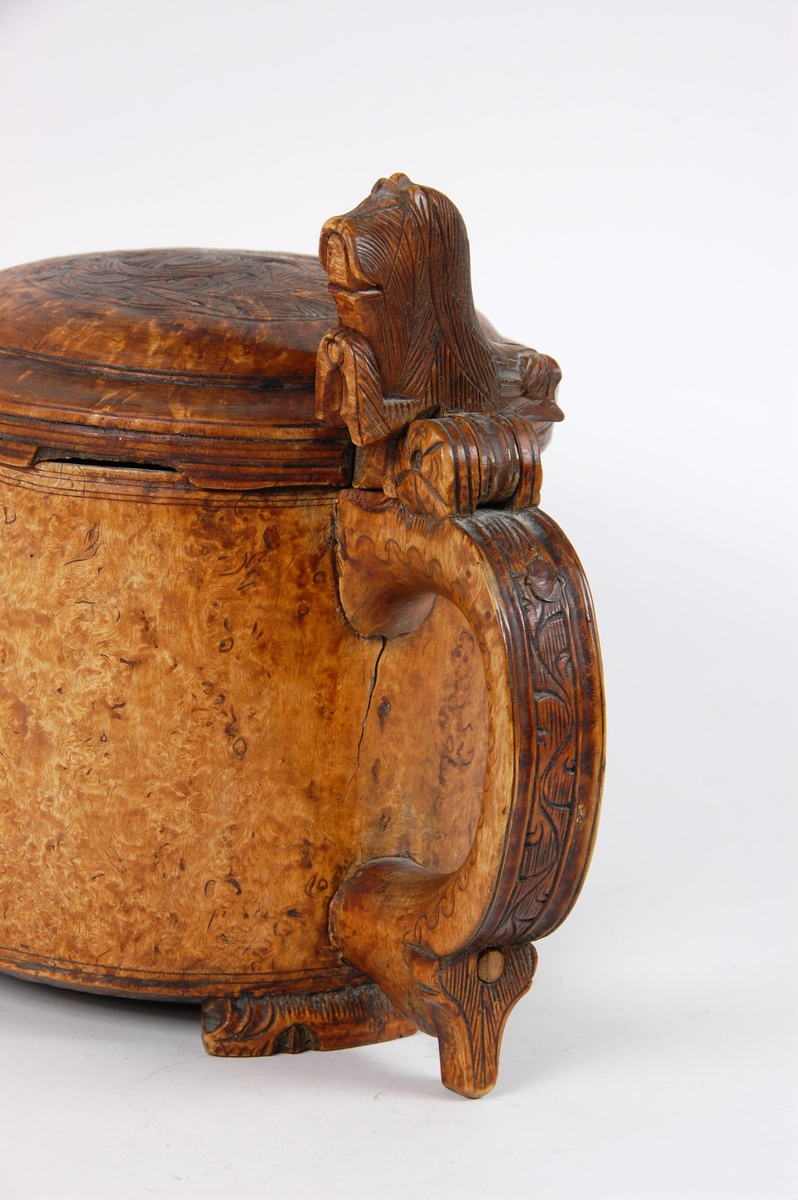 Kanne av dreid valbjørk. Lokk med akantusskurd. Løveformet lokkåpner. Hank med bladranke. Tre løveføtter.