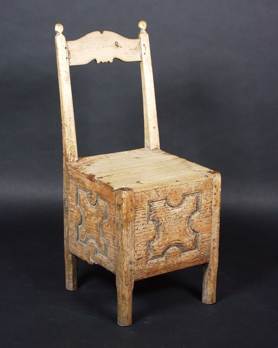 Stolen er av bjørk og furu, formet som nattstol,men med fast sete og høy rygg. Baksiden av toppstykket og sargen er utskåret.