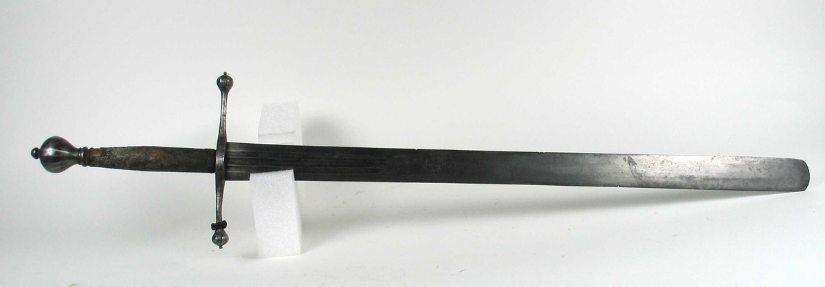 Skarprettersverd.  Pæreformet knapp med fasettetert dekor.
Tregrep viklet med rokkeskinn. 
Rette åttekantede parérstenger som ender i to dråper med kantet dekor. Rett tveegget klinge med ovalt tverrsnitt  og tre korte blodrender på hver side. Innslått tre smedstempler med kronede hoder.  På den ene siden er det gravert inn et hjul og på den andre siden en galge. Begge inngraveringer er innlagt med kobber.

