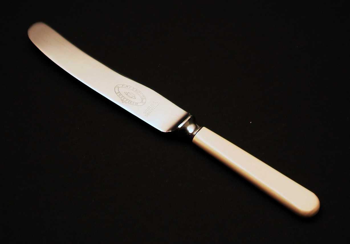 Bordkniv i stål med beige skaft i kunsstoff.