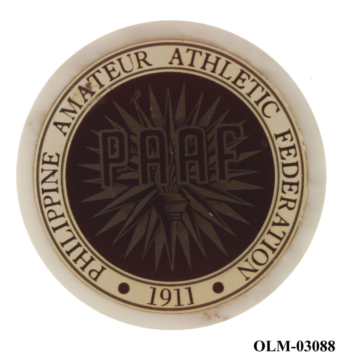 Hvit-, sort- og sølvfarget medalje av en type stenyøy- På medaljen er det logo for PAAF (Philippine Athletic Federation). I logoen inngår det en fakkel.
