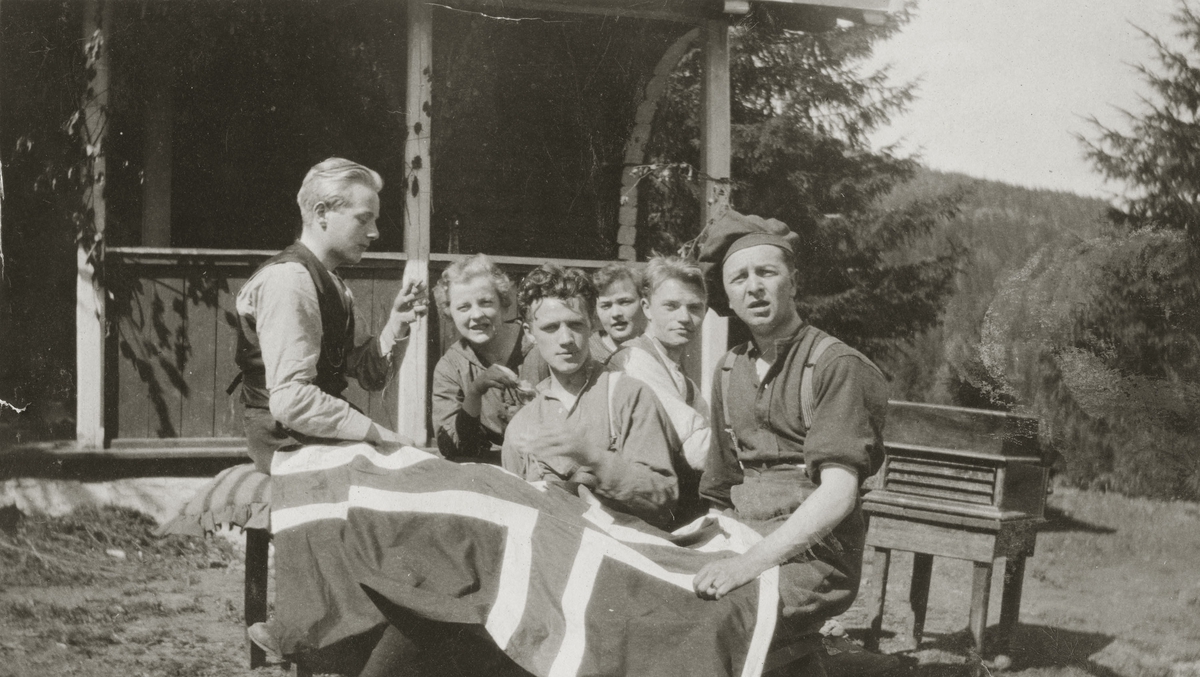 En gruppe ungdommer sitter i hagen med det Norske flagget.