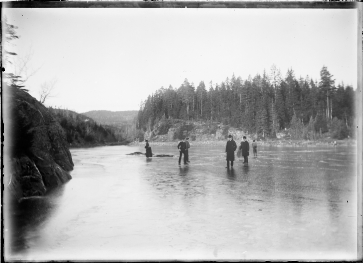 To damer og fem menn går over isen på Alunsjøen.