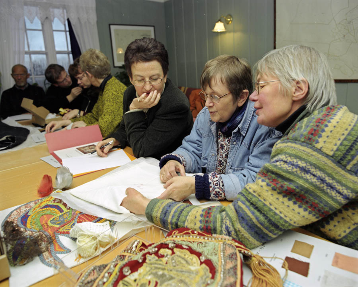 Akershus fylkesmuseum avholder kurs om bevaring av tekstiler. Kursholder og kursdeltagere i forskjelige situasjoner rundt et bord m tekstiler.