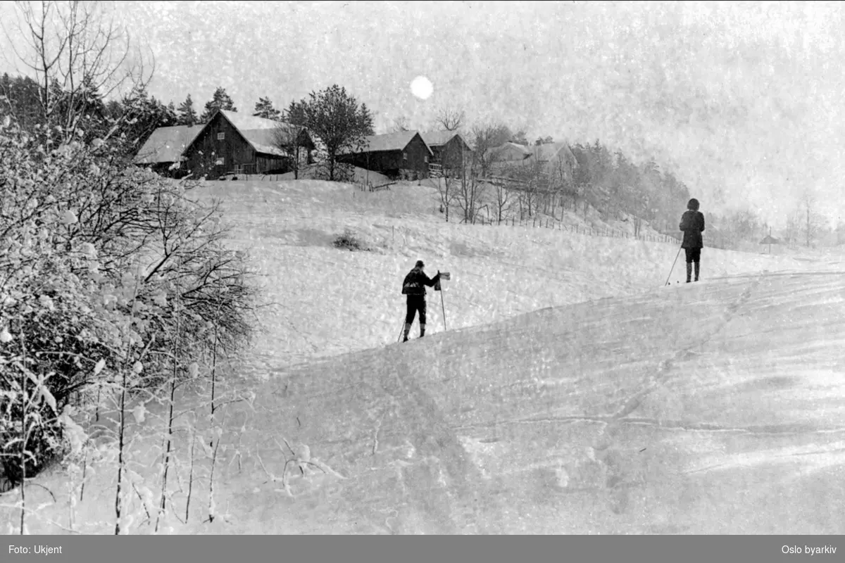 Nordre Dal gård. Fotografen har stått der hvor Vinterveien (gang og sykkelveien) går i dag.. Mann og kvinne på ski, vinter.