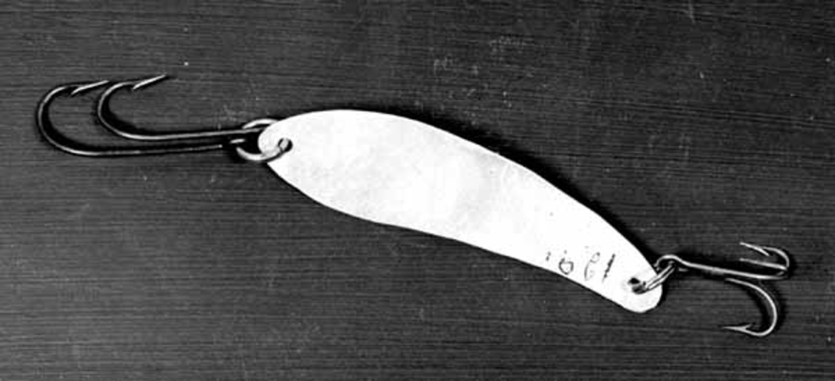 Hjemmelaget skjesluk, brukt av Brynjulf Styve. 
Sluken er av blankt blikk, med en 3-krok i smaleste enden og to enkeltkroker i andre enden. 
Sluken er helt flat. 
