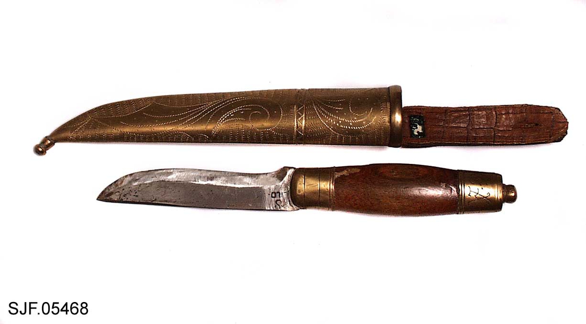 Kniven har brunbeiset skaft, antageligvis av bjørk. Slire og holker er av messing. Slira er foret med papp. Hempa er av imitert krokodilleskinn. Kniven er innkjøpt sammen med andre kniver i ei samling fra Birger Arntzen. 
