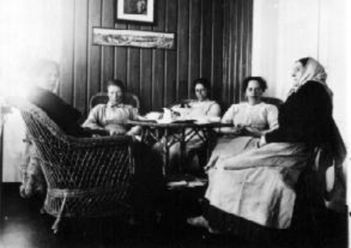 Interiør. Stue med kurvmøbler. Fem damer rundt bordet. Fra venstre er Eli Dobloug, Marthe Hovde, Mia Solhaug, Gønner, mor.