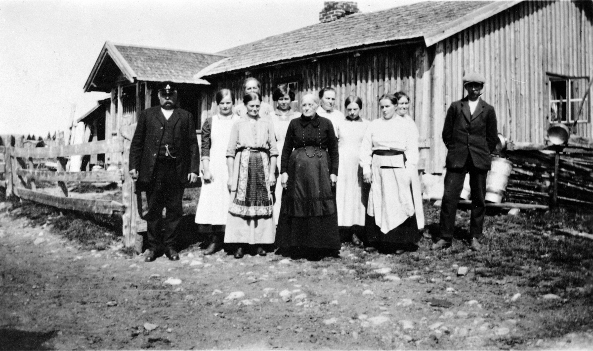 Gruppe personer utafor størhuset til Mørkved store på Nysætra. Til venstre er Thore Lien, dame i svart er Anne Lier, til venstre for henne er Oline Finstad, resten er ukjent. Ca. 1912.