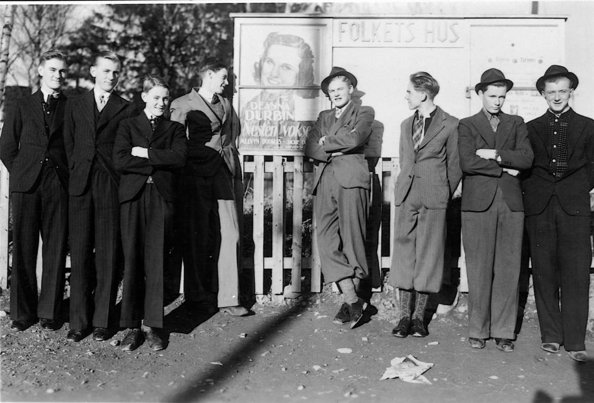 Kinotavla til Folkets Hus, Moelv. På plakaten er Deanna Durkin i filmen "Nesten voksen". Fra venstre er Leif Fruseth, Rolf Bakaas, Kjell Fruseth, Per Ulven, Johs. Løkkesveen, Sverre SImensen, Mentz Holmen, Reidar Bakaas. Ringsaker  1937-38.