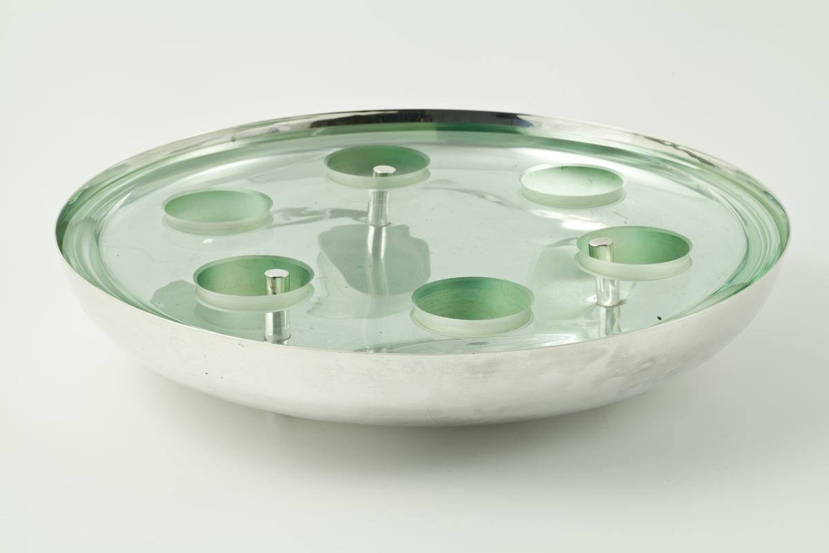En glassdisk med seks hull i er lagt i en metallbolle.