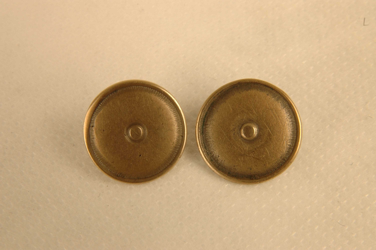 To tilnærmet like runde, støpte knapper med risset linje langs kanten og "knapp" innerst.