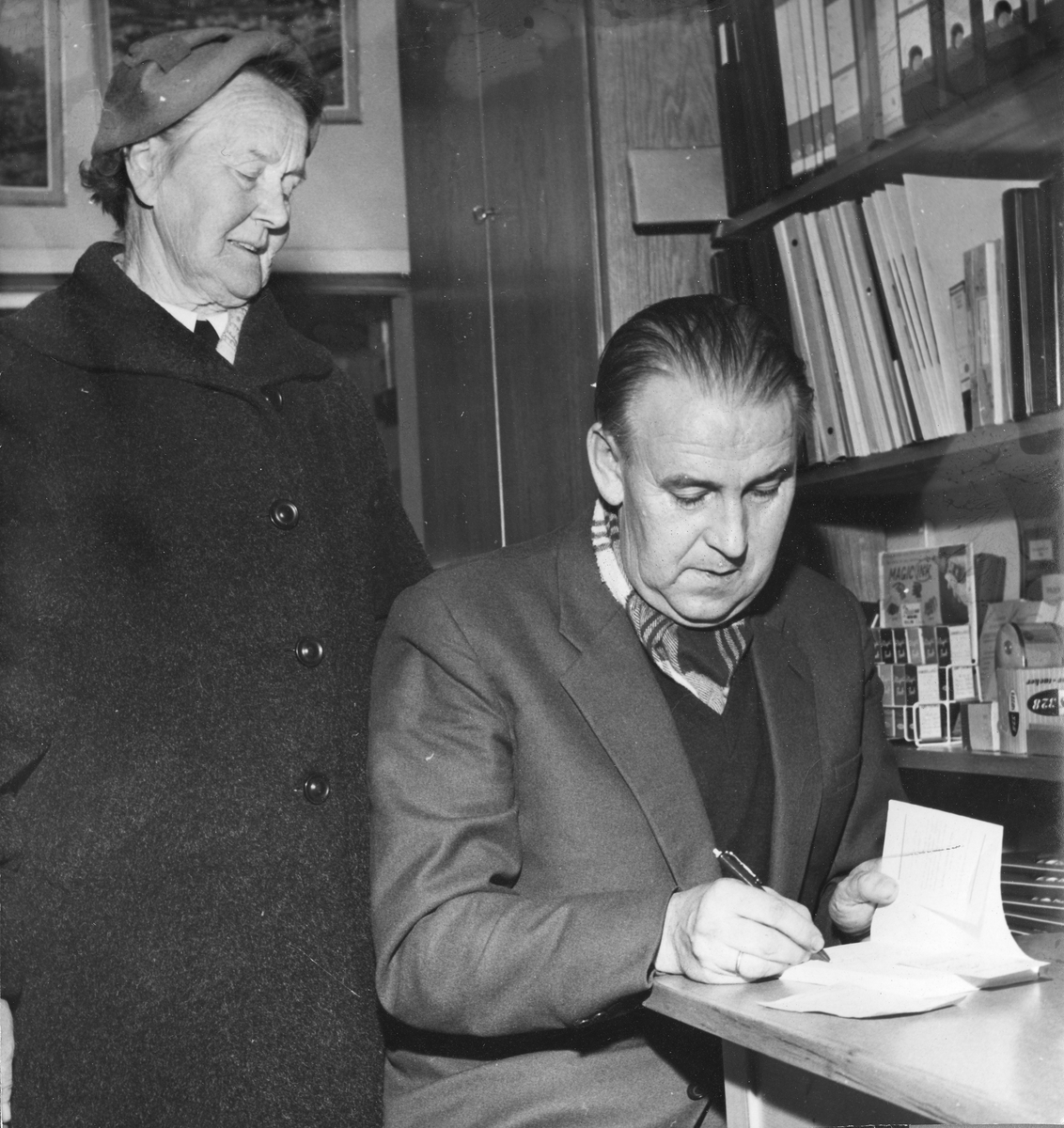 Alf Prøysen signerer bøker hos Gravdahl bokhandel i Hamar. Dame stående bak er ukjent.  (HS 3. NOVEMBER 1959)
Gravdahl bokhandel ble stiftet av Marcus Gravdahl i 1937, og er en av de eldste lokalt eide butikker i Hamar. Gravdahl åpnet sin bokhandel i Granerudgården i Torggata på Hamar, hvor den fortsatt har sine lokaler. Her jobbet dikteren Rolf Jacobsen en periode på 50-tallet.