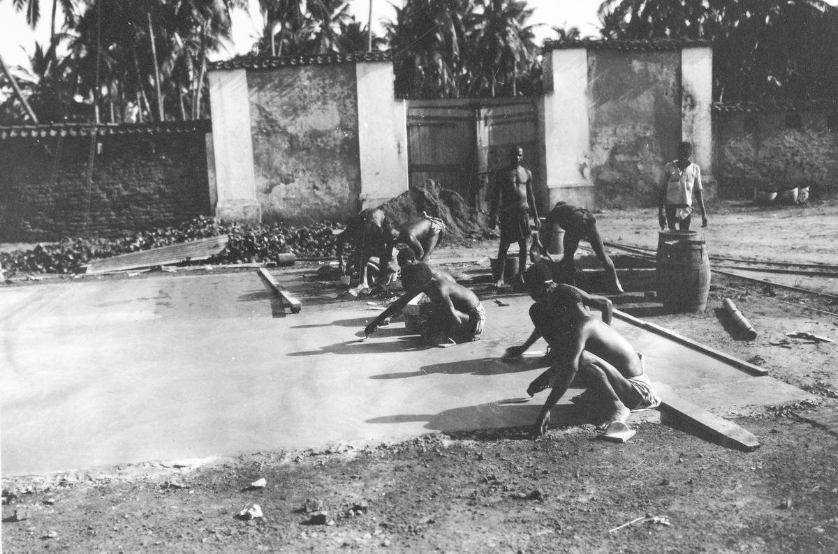 Mosambik 1914. Unge afrikanske arbeidere i ferd med  støpe et gulv.