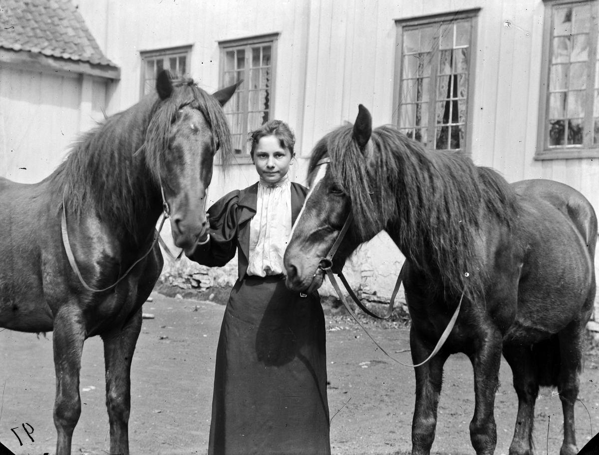 Hovinsholm gård, Helgøya i Ringsaker. Ragnhild Marie Hoel (f.1877)  med to hester på indre gårdsplass. Foto Jacob Hoel 1897.